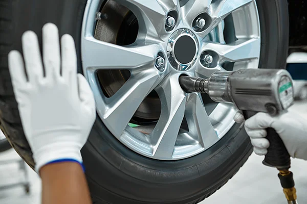 technician using an impact wrench to attach a wheel to a car