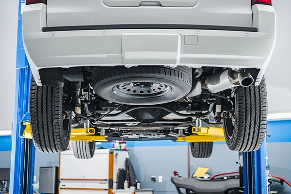 Underside of vehicle on lift showing suspension setup and spare tire